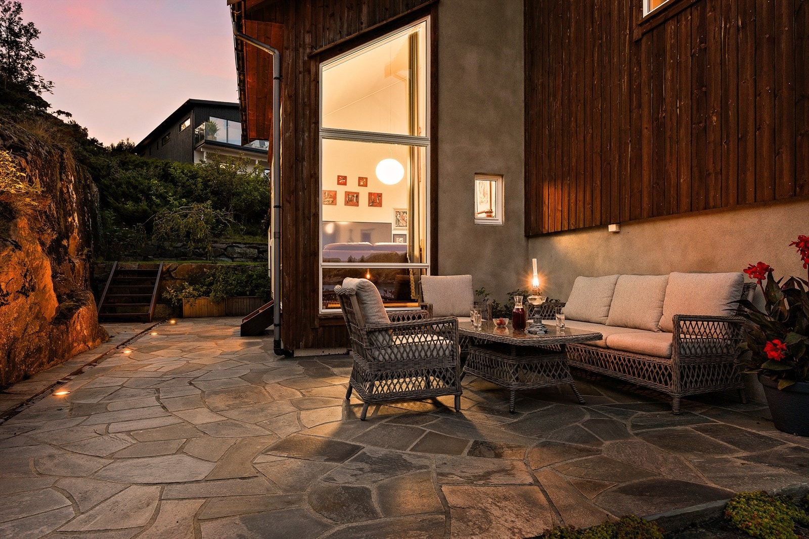 Den lettstelte tomten er pent opparbeidet og innbydende med en kombinasjon av plen, beplantede områder, skiferplatting og lødd naturstein. Galleribilde