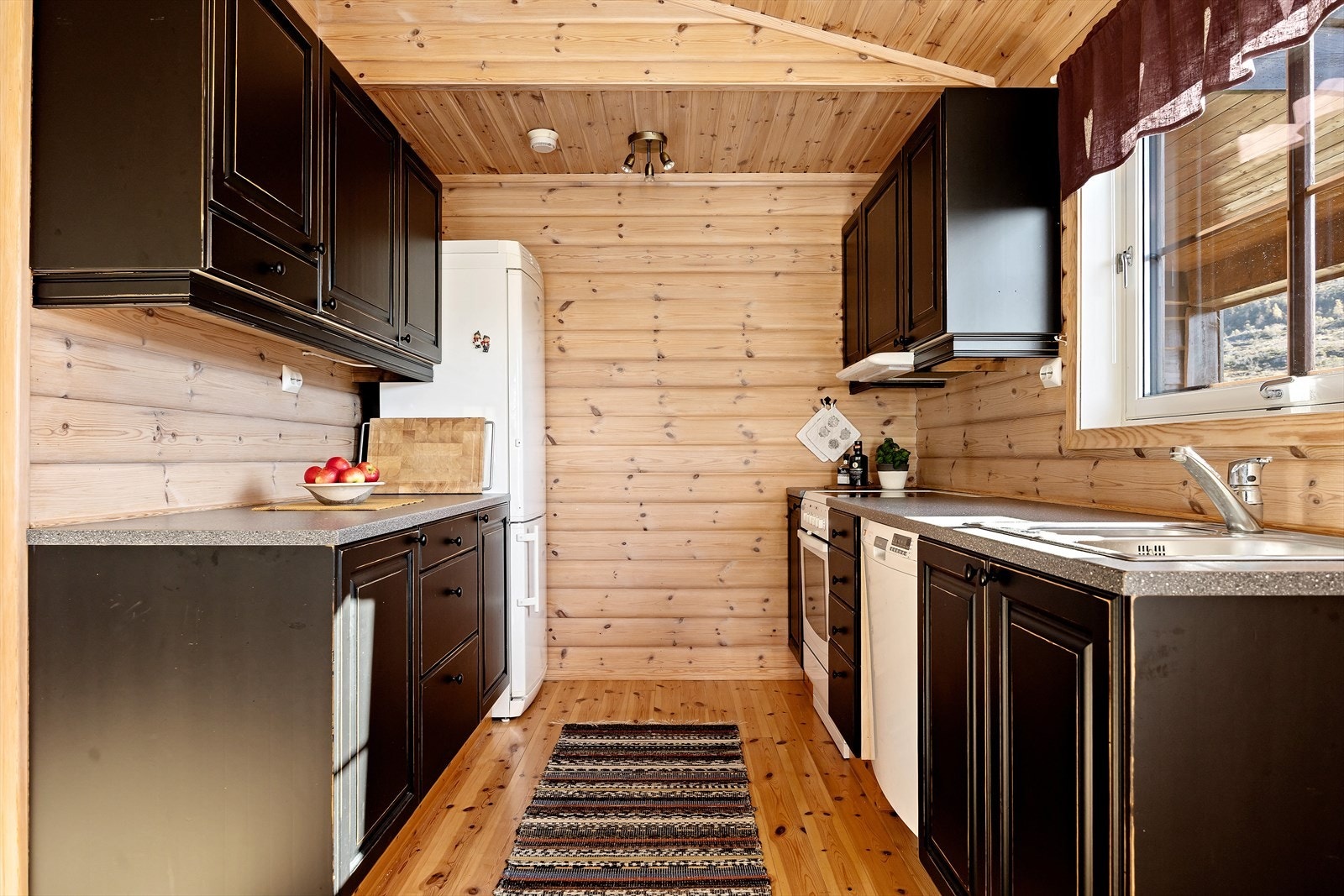 Kjøkkenet har mørke profilerte fronter som gir rommet et eksklusivt preg. Laminat benkeplate gir god arbeidsplass, og hvitevarer som oppvaskmaskin, komfyr og frittstående kjøleskap medfølger. Galleribilde