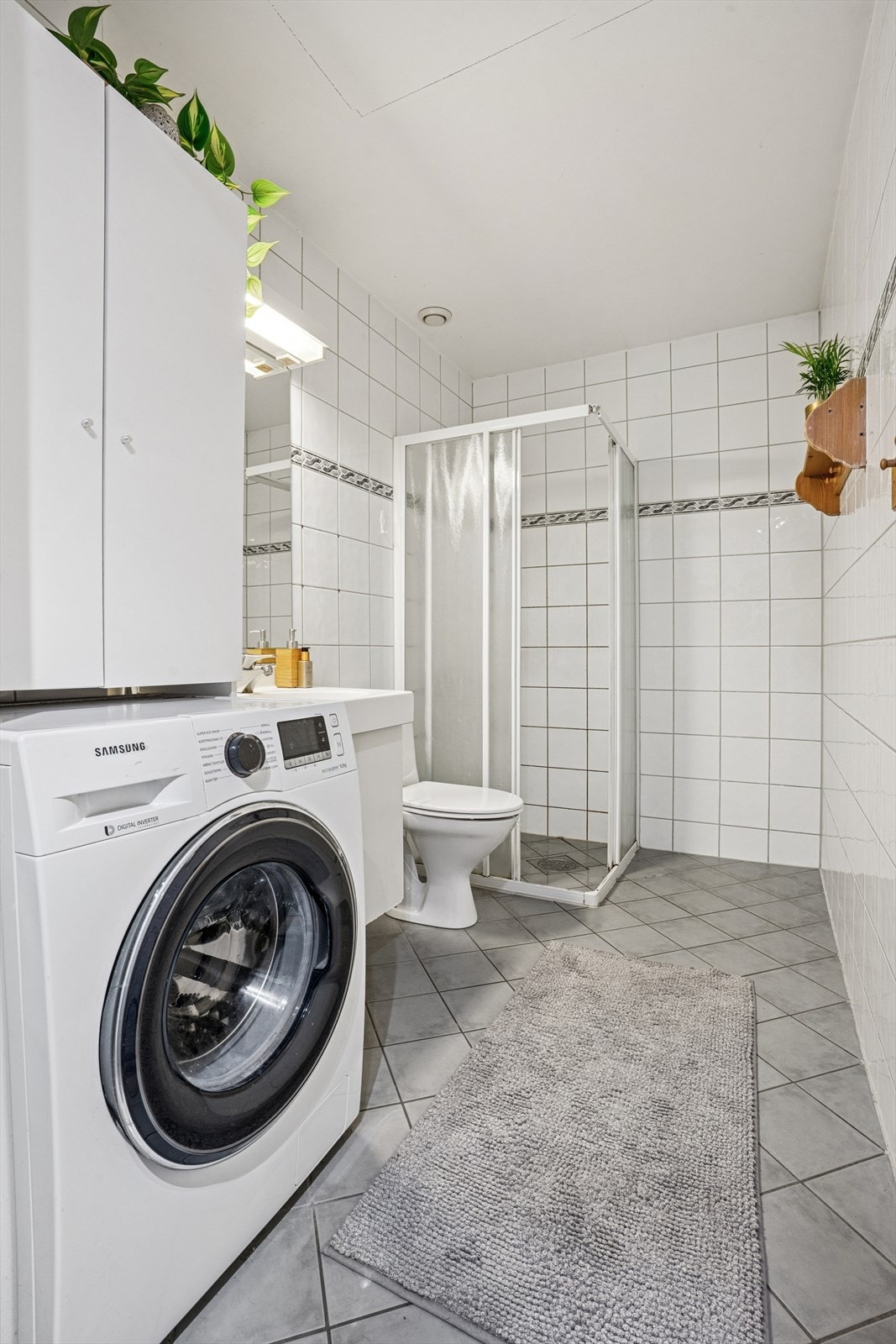 Flislagt bad i underetasjen med dusjhjørne og opplegg for vaskemaskin. Galleribilde