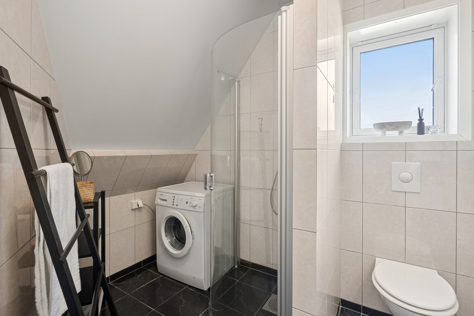 Dusjhjørne med glassvegger og opplegg til vaskemaskin gir praktisk bruk. Galleribilde