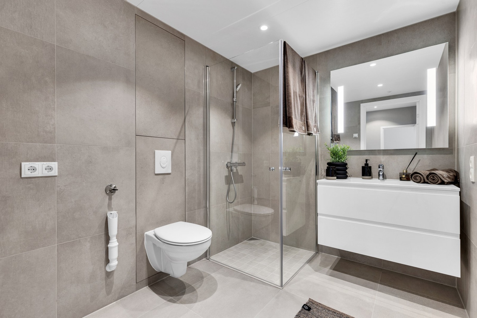 Delikat, flislagt bad med gulvvarme og downlights i himling Galleribilde