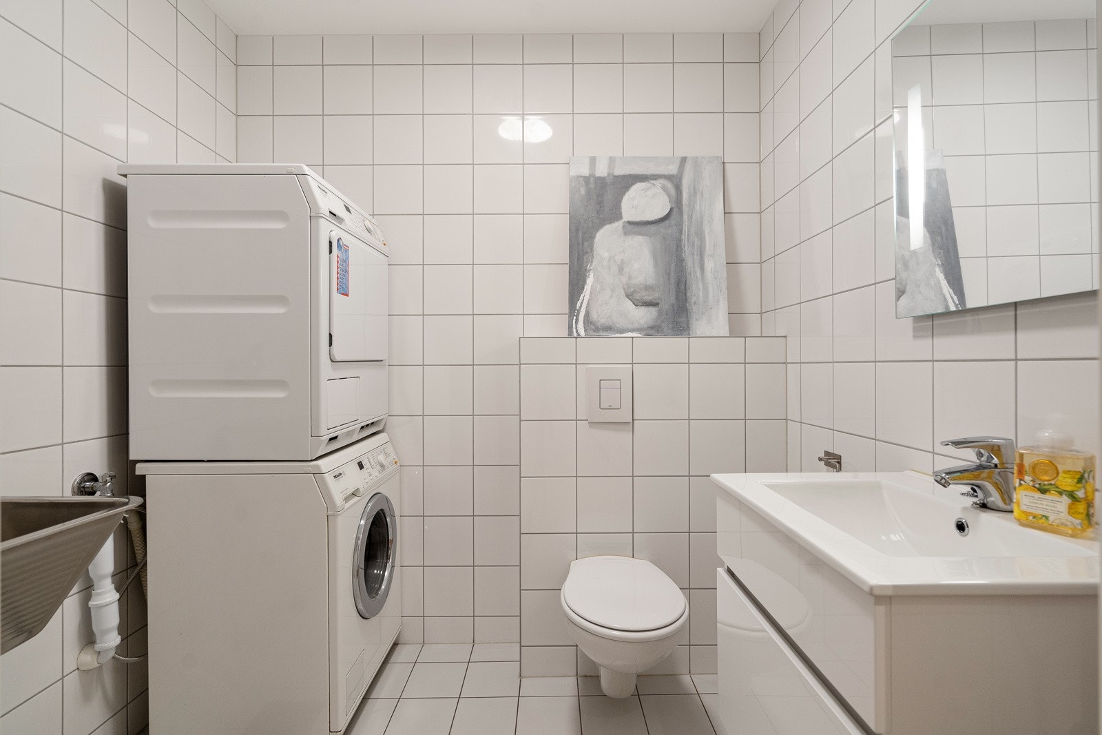 Vaskerommet har utslagsvask og veggmontert toalett Galleribilde
