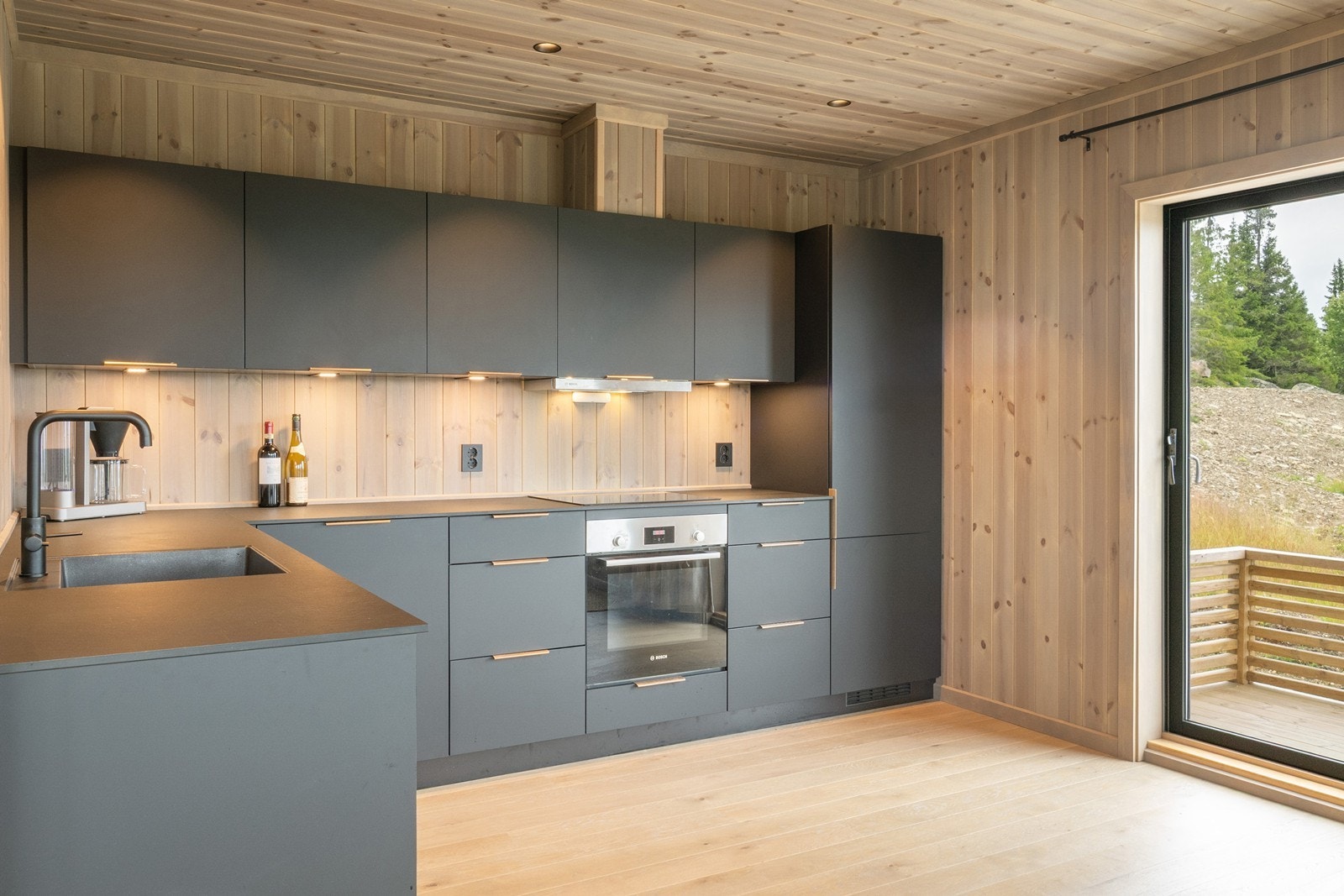 Innredningen fra Kvik har sorte, glatte fronter, bronsefargede detaljer og matchende laminatbenkeplate med sort kum. Galleribilde