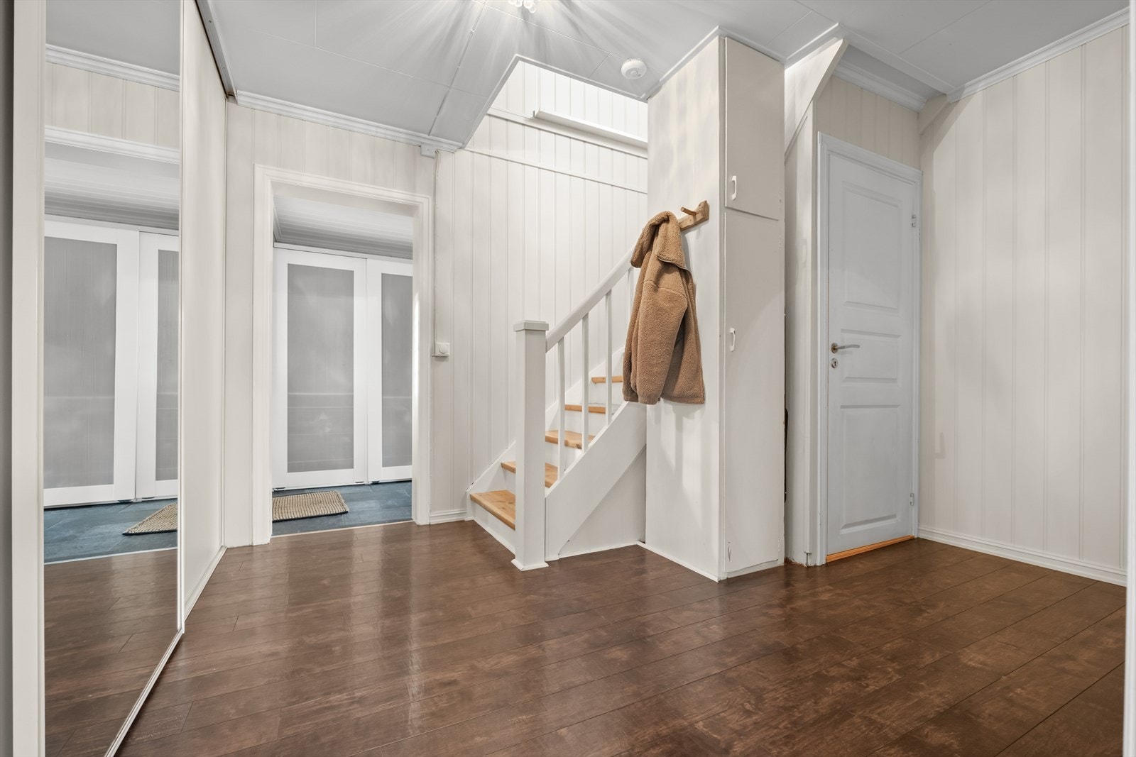 Romslig hall/trapperom med skyvedørsgarderobe i forbindelse med inngangspartiet. Galleribilde
