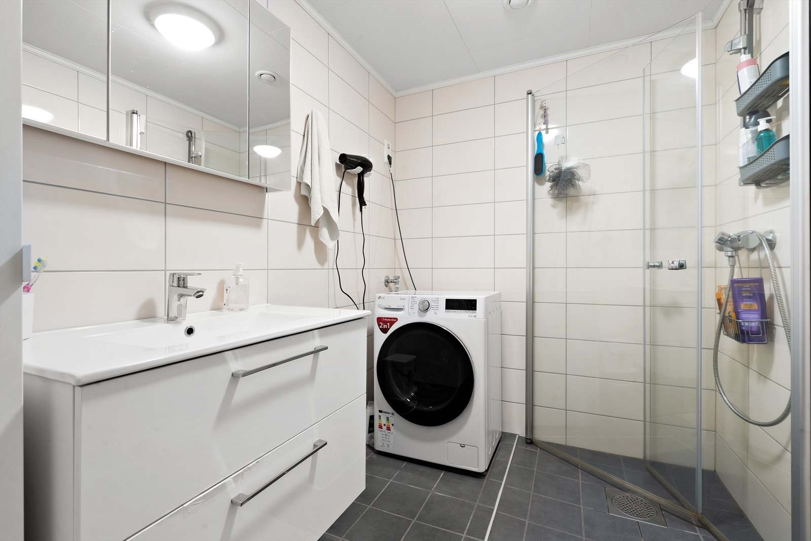 Pent flislagt bad med dusjhjørne og opplegg for vaskemaskin. Galleribilde