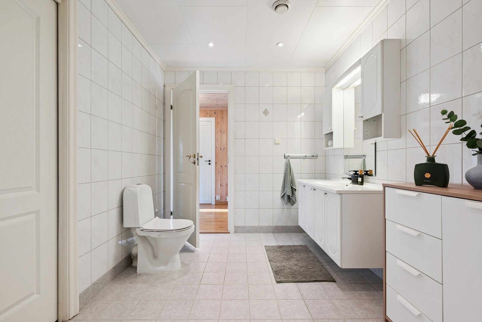 Badet er innredet med dusj med glassvegger, gulvmontert WC og servant med over- og underskap. Galleribilde