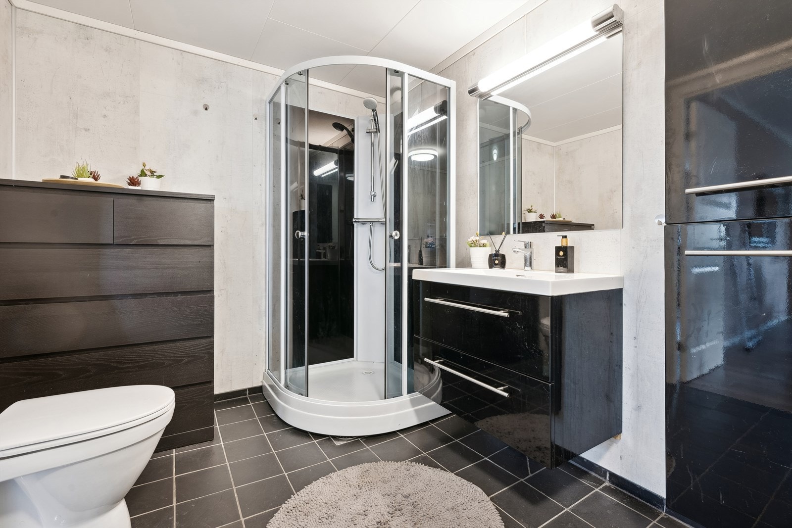 Badet er innredet med dusjkabinett, klosett, servant på skuffeseksjon og det er opplegg for vaskemaskin. Galleribilde