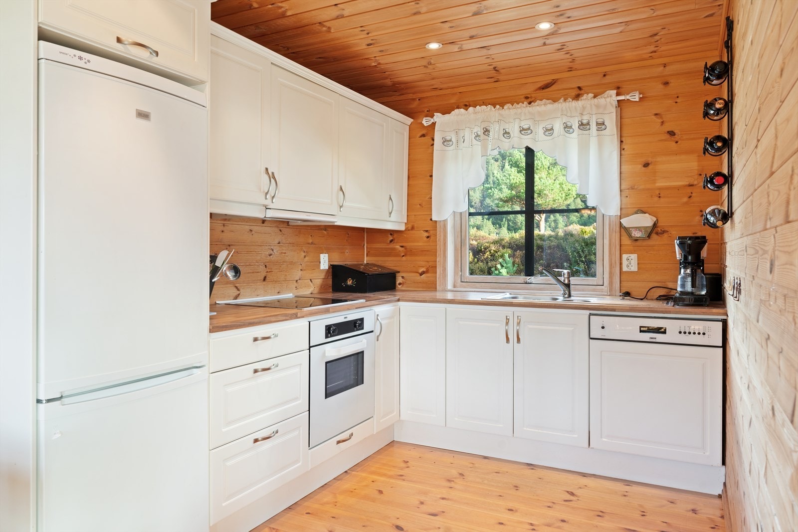 Lyst og tidløst kjøkken med profilierte fronter og laminert benkeplate som harmonerer med hyttas naturlige stil. Galleribilde