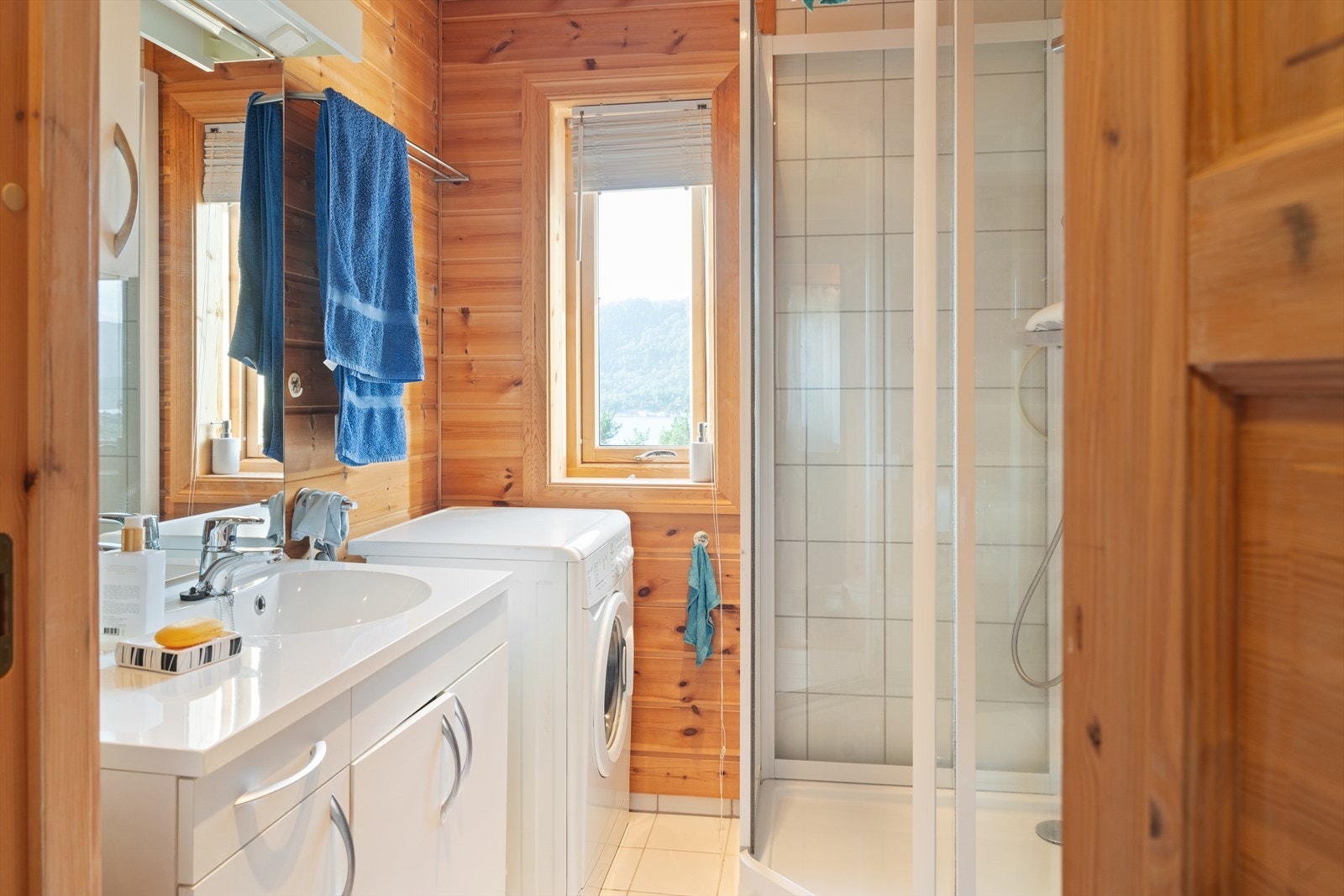 Lyst og koselig bad med fliselagt gulv, med god standard og gjennomført hyttestil. Rommet er innredet med dusjkabinett, servant med underskap og toalett. Her er det også plass til vaskemaskin - praktisk for lengre opphold og familieturer. Galleribilde