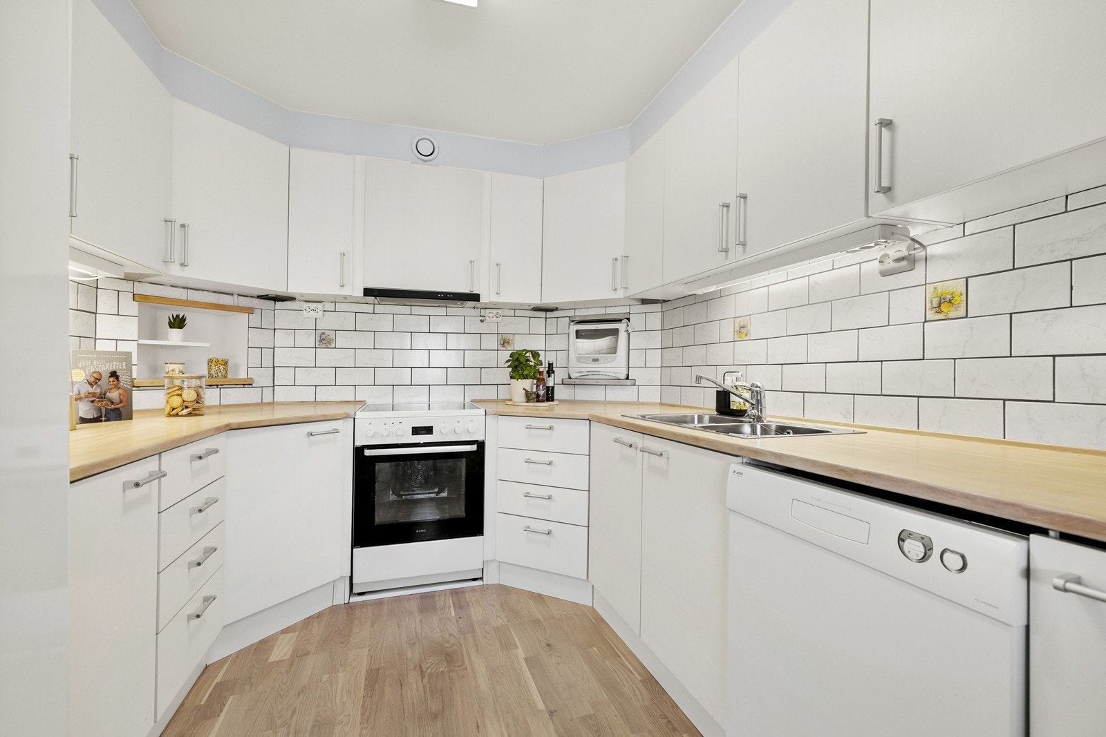 Kjøkkenet har innredning med glatte fronter. Benkeplaten er av heltre. Det er kjøl/fryseskap, oppvaskmaskin, komfyr og micro. Det er kjøkkenventilator med kullfilter. Galleribilde