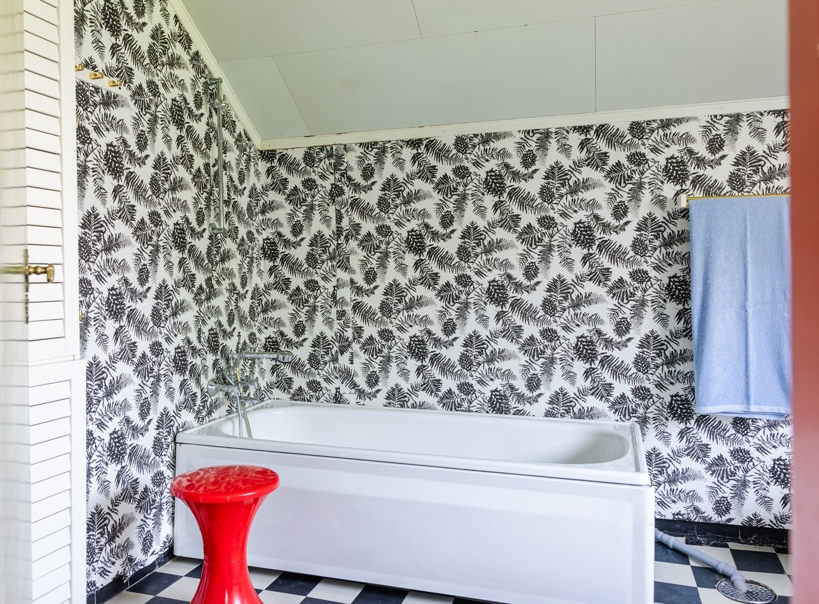 Bad i 2. etasje har mønstret tapet på vegger og sjakkmønstrede fliser på gulv. Her er et badekar til glede for liten og stor. Galleribilde