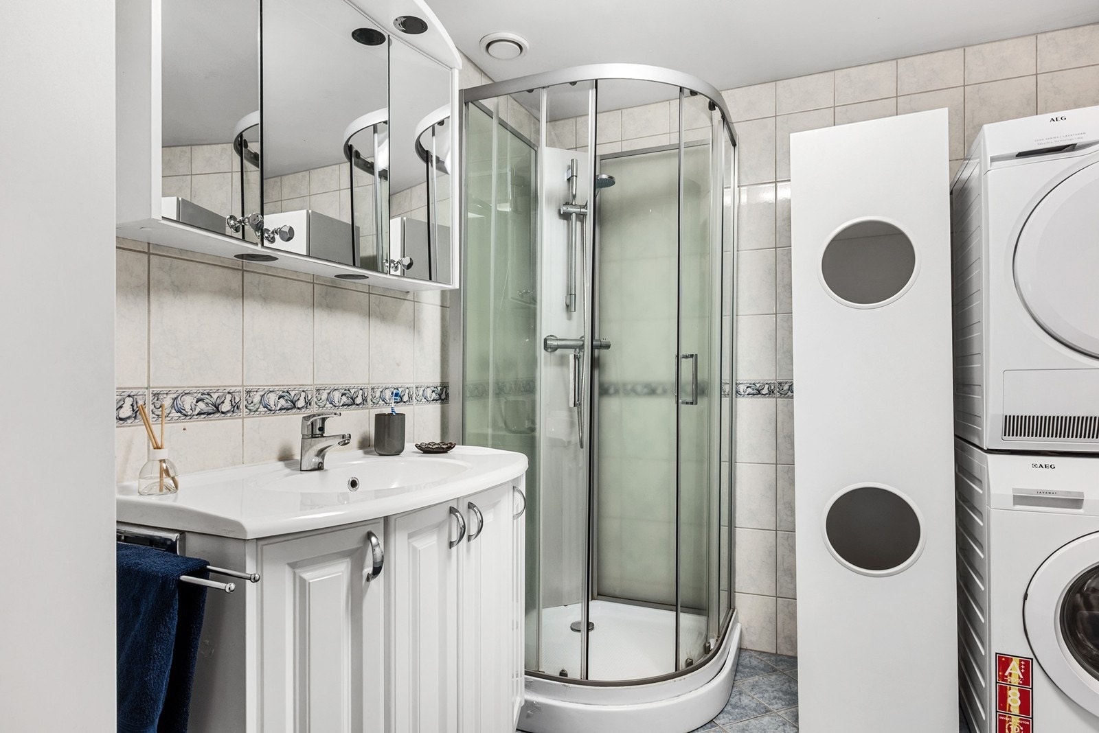 Rommet er innredet med dusjkabinett, gulvfestet toalett, servantskap med nedfelt servant og speilskap. For klesvask er det opplegg for vaskemaskin og tørketrommel. Galleribilde