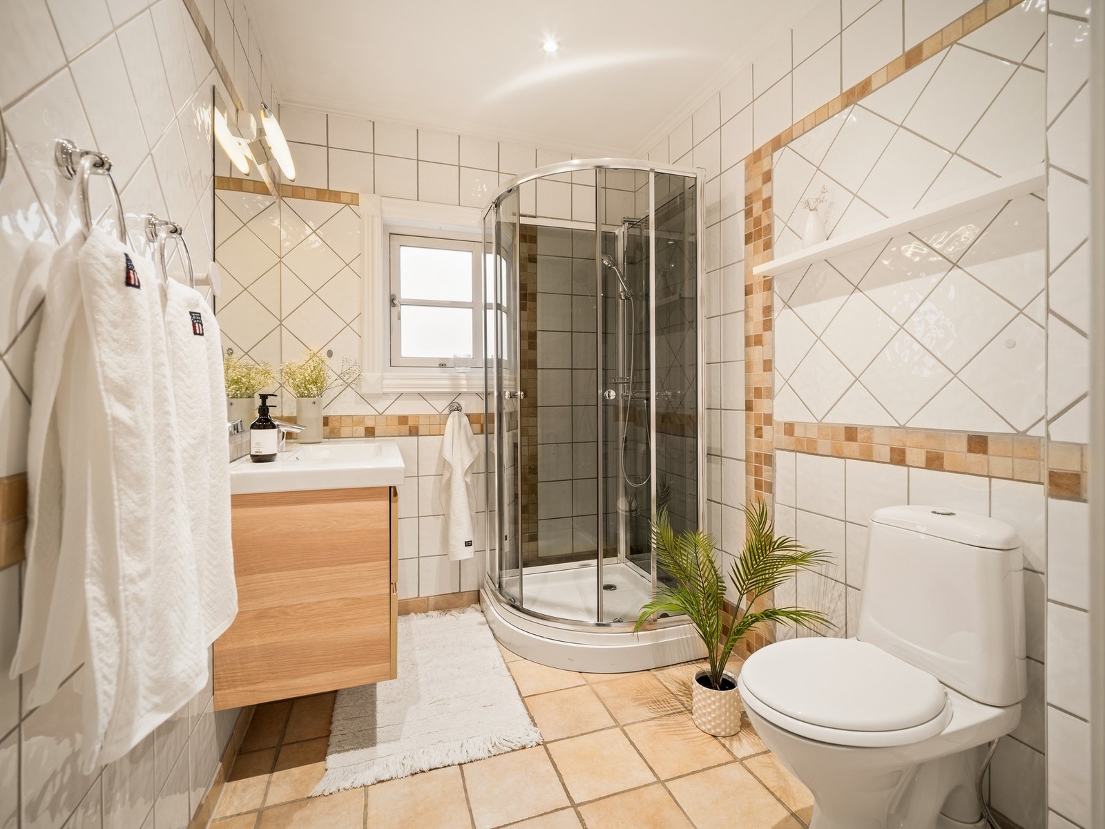 Det flislagte badet i 1. etasje har gulv med varmekabler og er utstyrt med servantskap, dusjkabinett og gulvstående toalett. Galleribilde