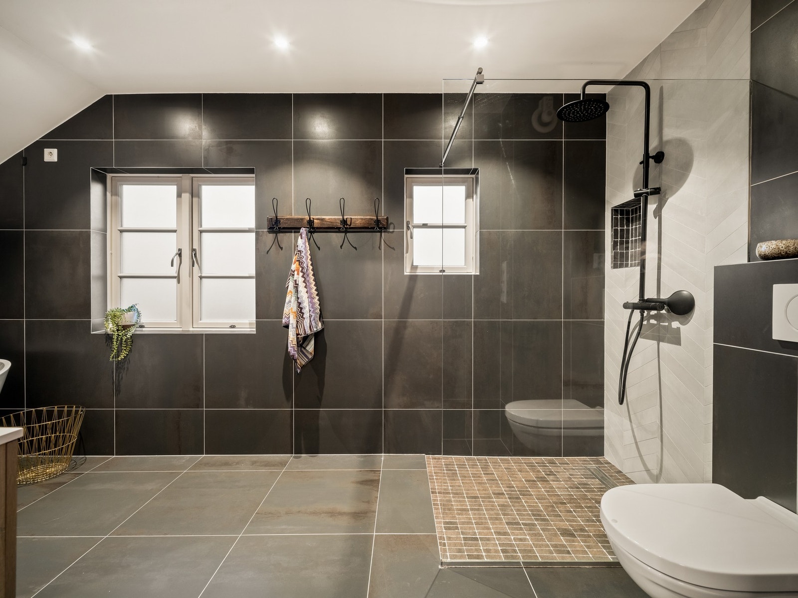 Badet i 2. etasje ble oppgradert i 2019 og har et stilrent uttrykk med fliser på gulv og vegger, varmekabler, servantinnredning, dusjhjørne, badekar og vegghengt toalett. Galleribilde