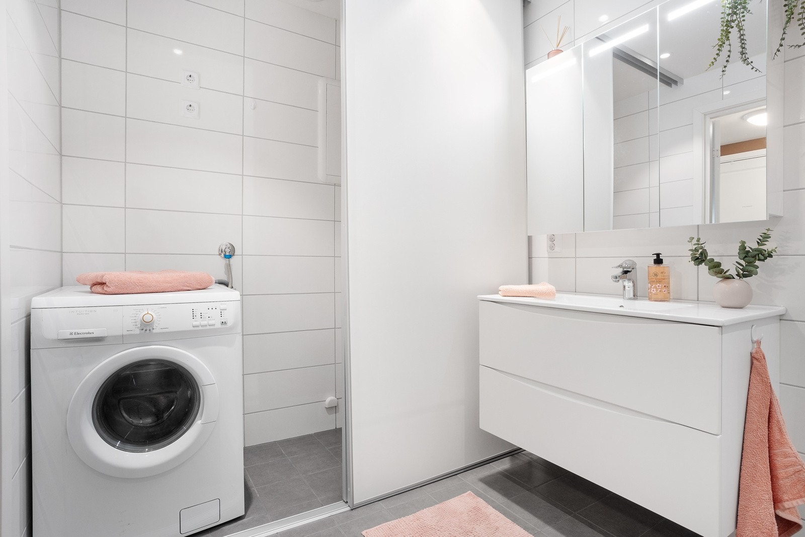 På badet skjules en praktisk vaskeromsløsning bak skyvedør. Opplegg for vaskemaskin og tørketrommel. Galleribilde