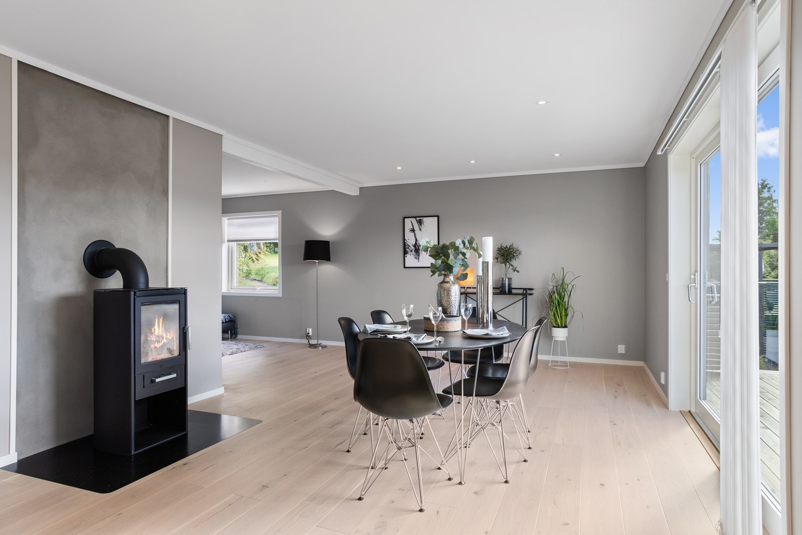 Den nyere og varmeeffektive peisovnen med glassdør er sentralt plassert i rommet, ut for spisestueplassen. Galleribilde