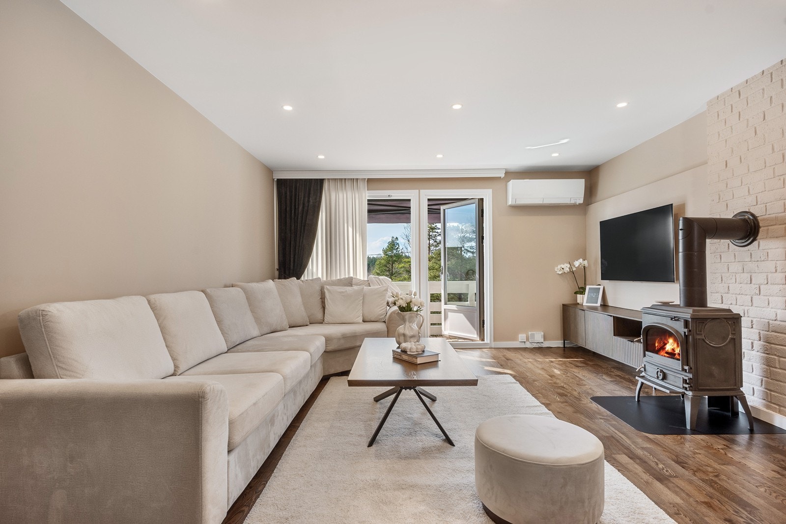 Stuen har plass til stort sofahjørne med TV-løsning, og et ildsted sørger for peiskos og varme på kjølige dager. Galleribilde