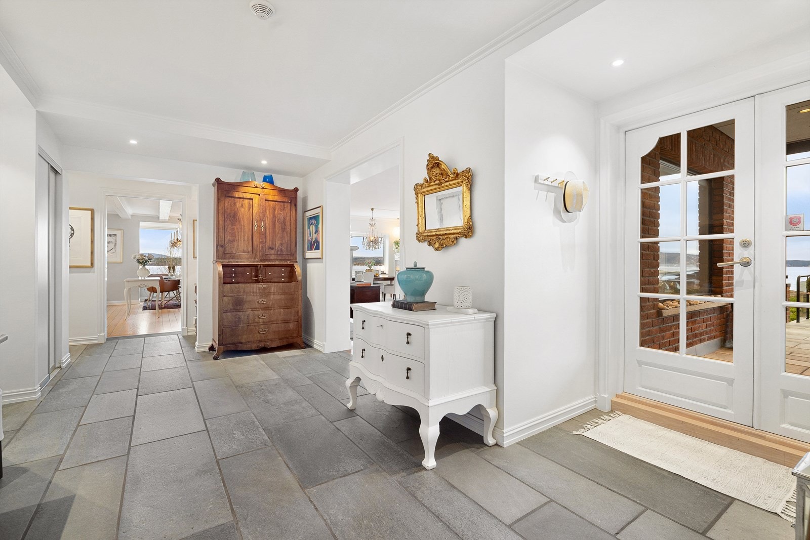 Den lekre hallen har skiferfliser på gulv med varmekabler for ekstra komfort og innfelte spotter i nedsenket himling. Galleribilde