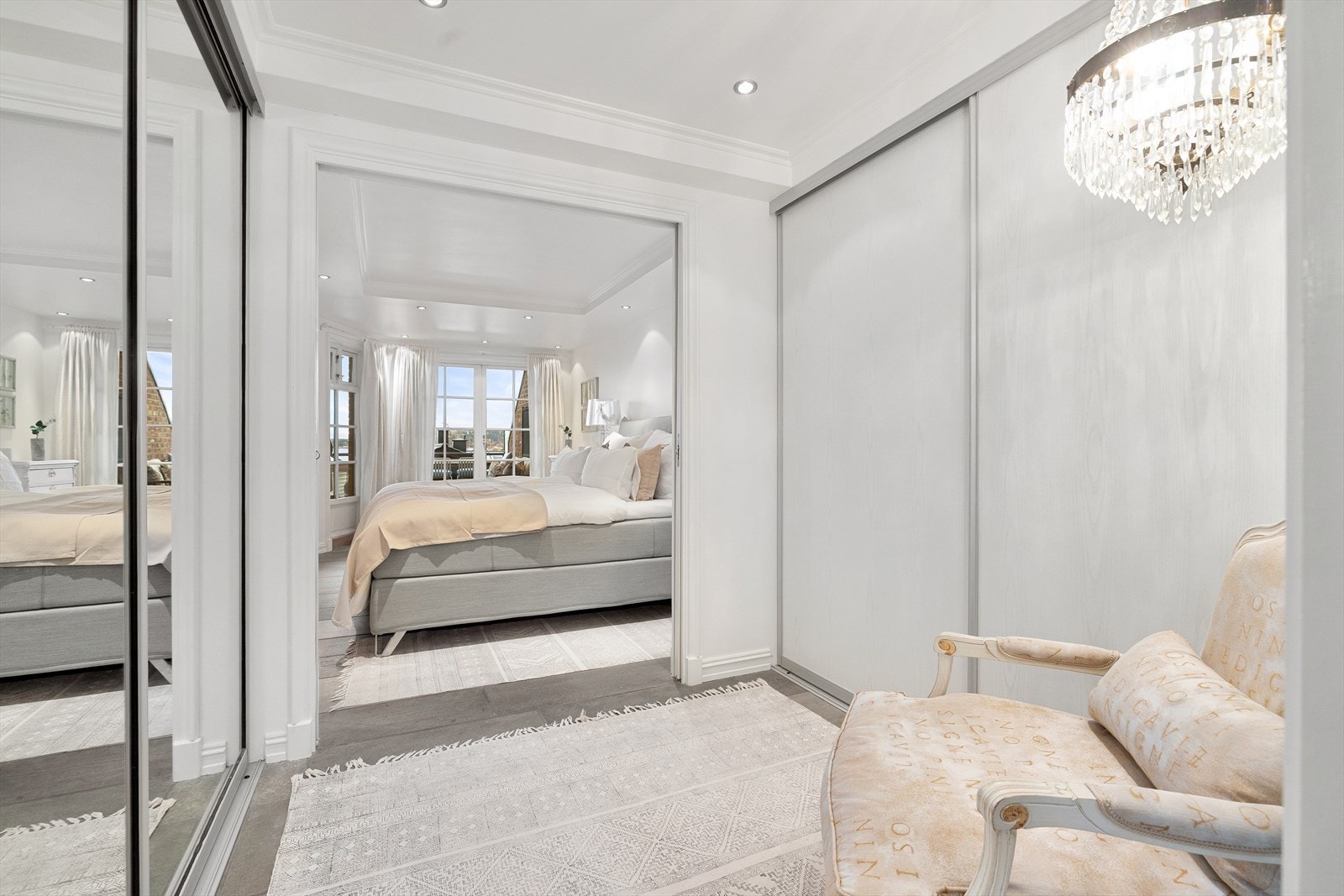 Praktisk omkledningsrom/ walk-in-closet med downligts i himling og to store skyvedørsgarderober plassert på hver side. Galleribilde