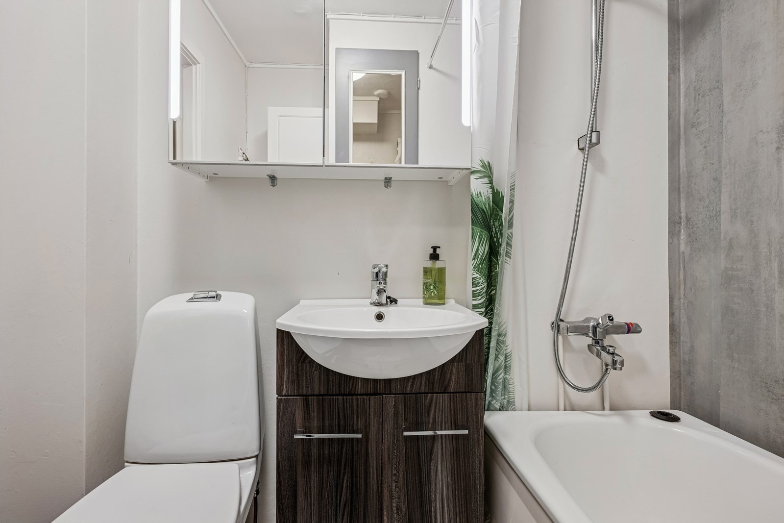 Badet er utstyrt med badekar med dusjløsning, gulvstående toalett og en flott baderomsinnredning. Galleribilde