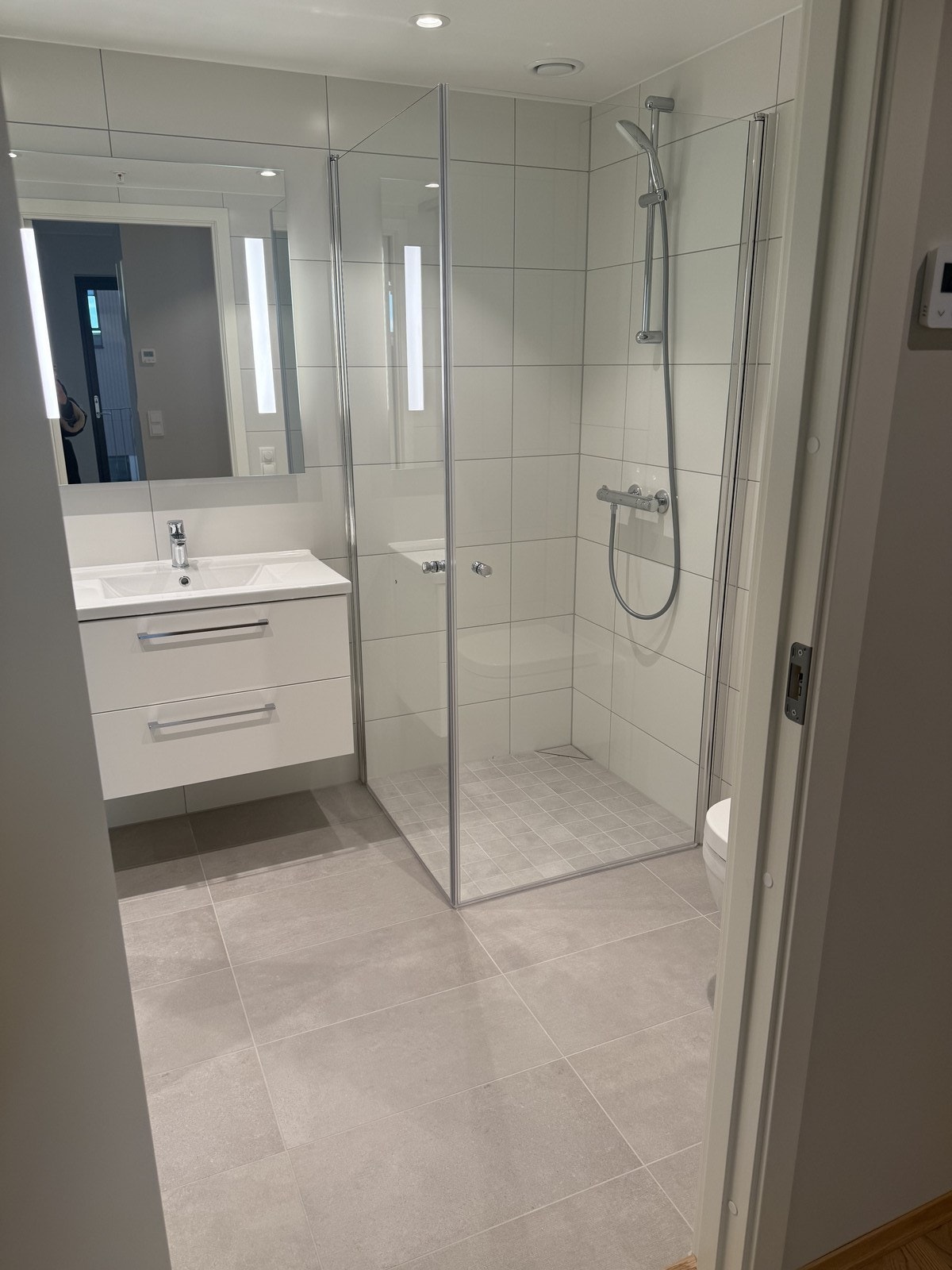 Pent flislagt bad med innfellbare dusjvegger og servant med underskuffer. Galleribilde