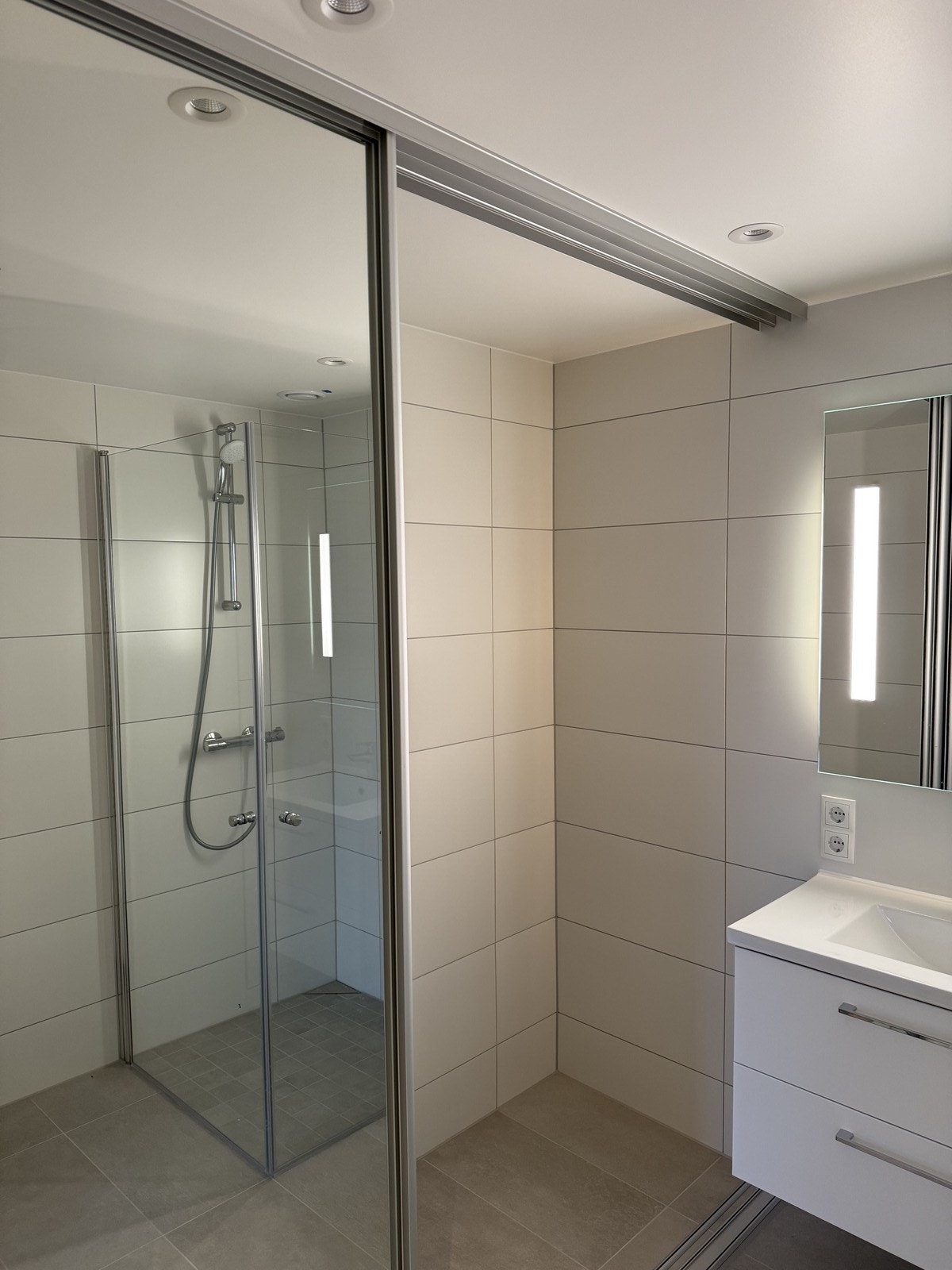 Speilskyvedør på badet, med opplegg til vaskemaskin og tørketrommel bak dørene. Galleribilde