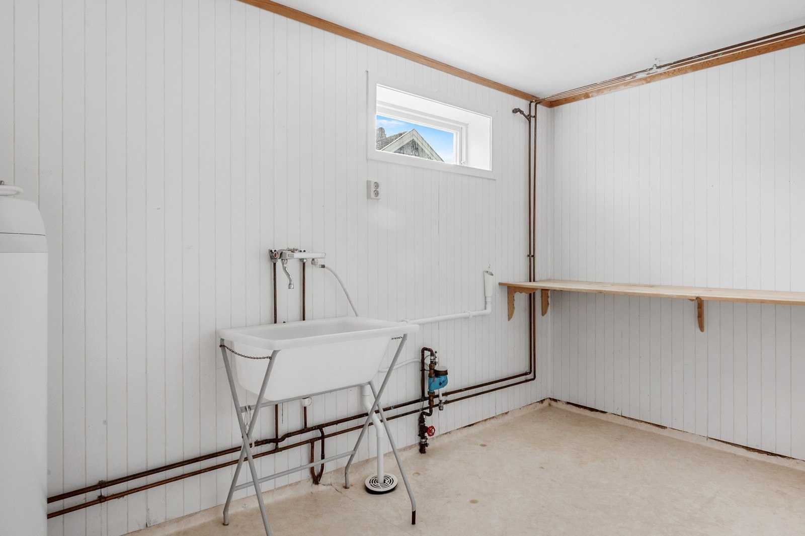 Vaskerom fra byggeår. Rommet har tapet på vegg, gulvbelegg med hulkil, utslagsvask i plast på stativ og mekanisk avtrekk. Røropplegg for vaskemaskin. Galleribilde