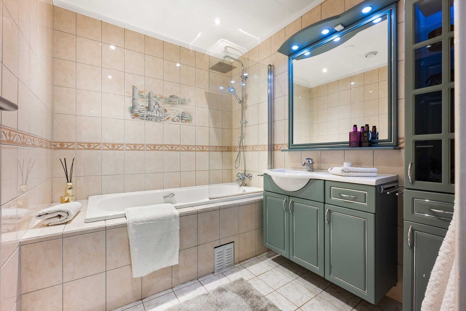 Romslig flislagt bad med badekar. Det er godt med oppbevaringsplass i baderomsinnredning Galleribilde