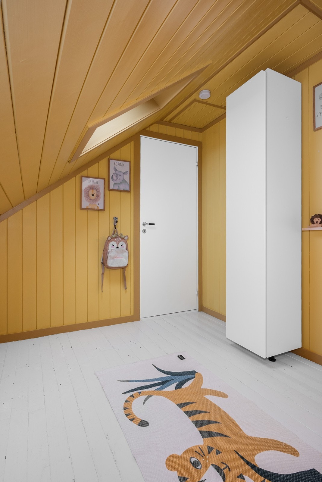 Et sjarmerende barnerom med skråtak og varme fargetoner som skaper en koselig stemning. Galleribilde