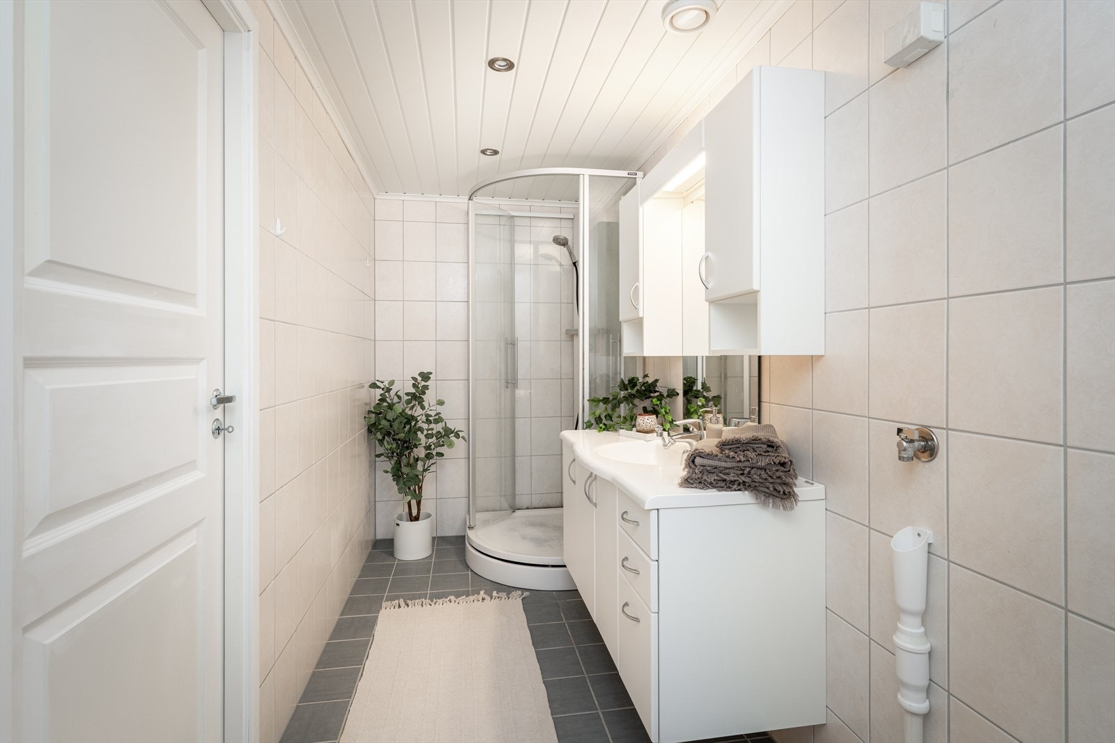 Badet er innredet med toalett, dusjkabinett og servantinnredning med skap, skuffer og speil. Galleribilde