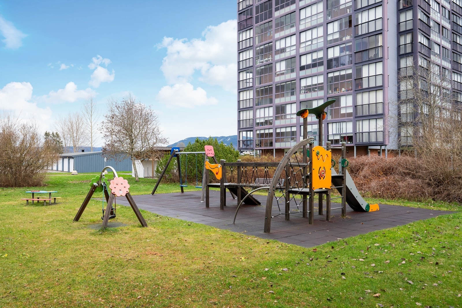 Tomten er pent opparbeidet med gressplen og variert beplantning, samt sosiale fellesområder med sitteplasser og lekeapparat. Galleribilde