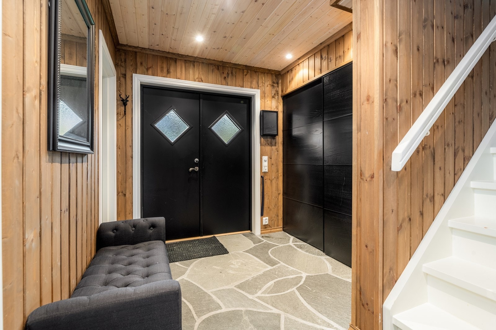 Fra delvis overbygget inngangsparti kommer man inn i en lun og praktisk hall som er utstyrt med skiferfliser med varme på gulv og stor skyvedørsgarderobe til oppbevaring av yttertøy. Galleribilde