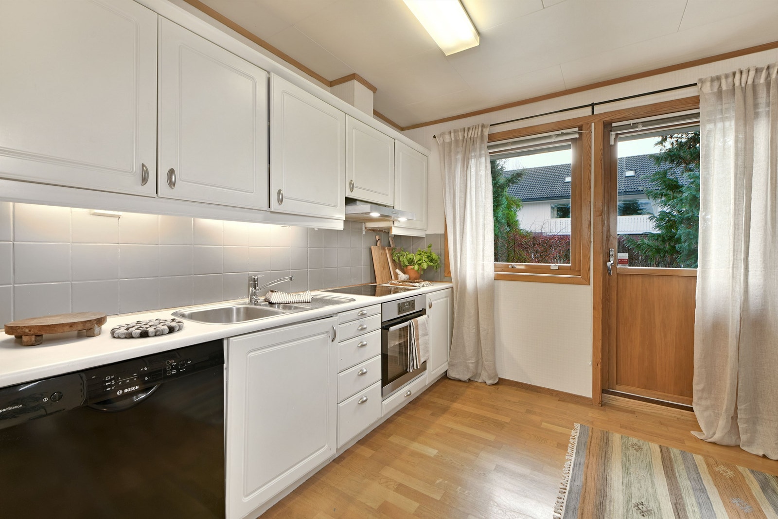 Kjøkken- hvite, profilerte fronter og fliser mellom over- og underskap - integrert koketopp, stekeovn og delvis integrert oppvaskmaskin medfølger Galleribilde