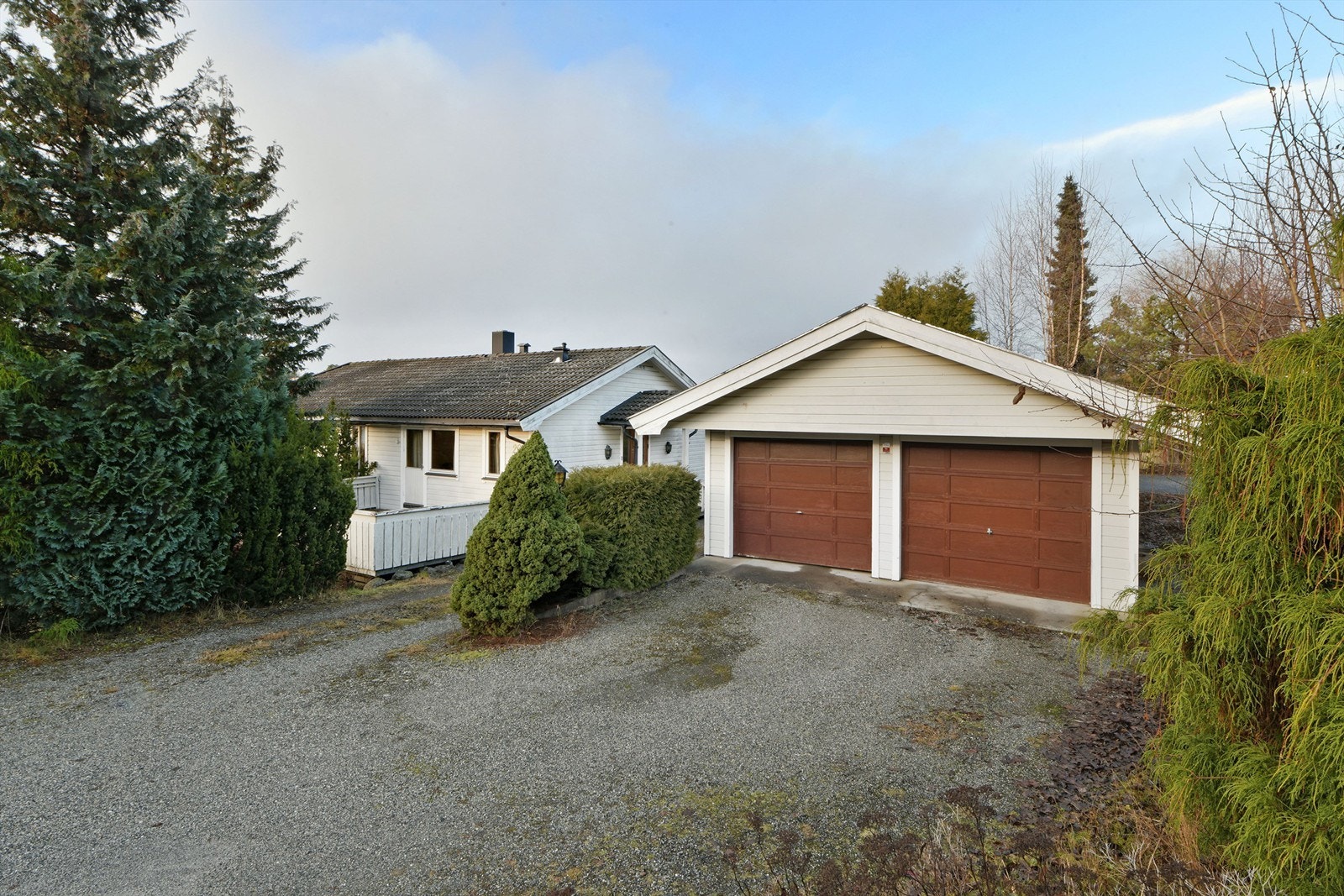 Dobbeltgarasje - ved innkjørselen ligger garasje med plass til flere biler på gruset gårdsplass Galleribilde