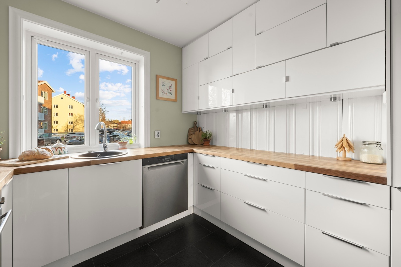 Innredningen består av glatte kjøkkenfronter, benkeplate i tre, belysning under overskap og kum med ett-greps blandebatteri Galleribilde