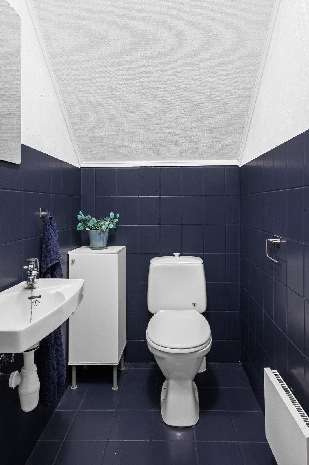 Toalettrom i 2. etasje har malte fliser, gulvfestet toalett og enkel vegghengt servant. Galleribilde