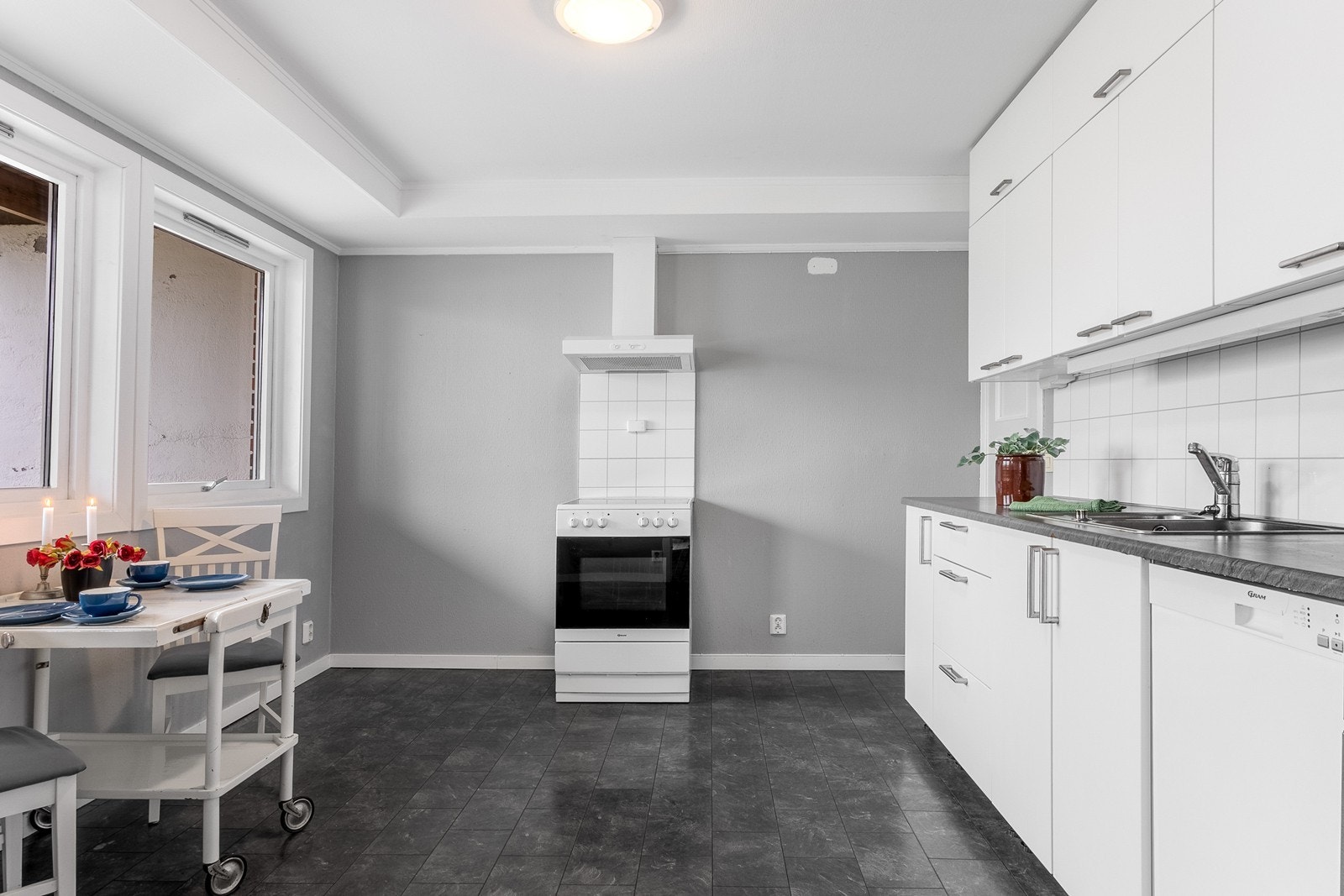 Kjøkkenet har rom for spiseplass ved vinduer. Innredningen har hvite, slette fronter, benkeplate i laminat og beskyttelsesplater på vegg over benk. Hvitevarene medfølger. Galleribilde