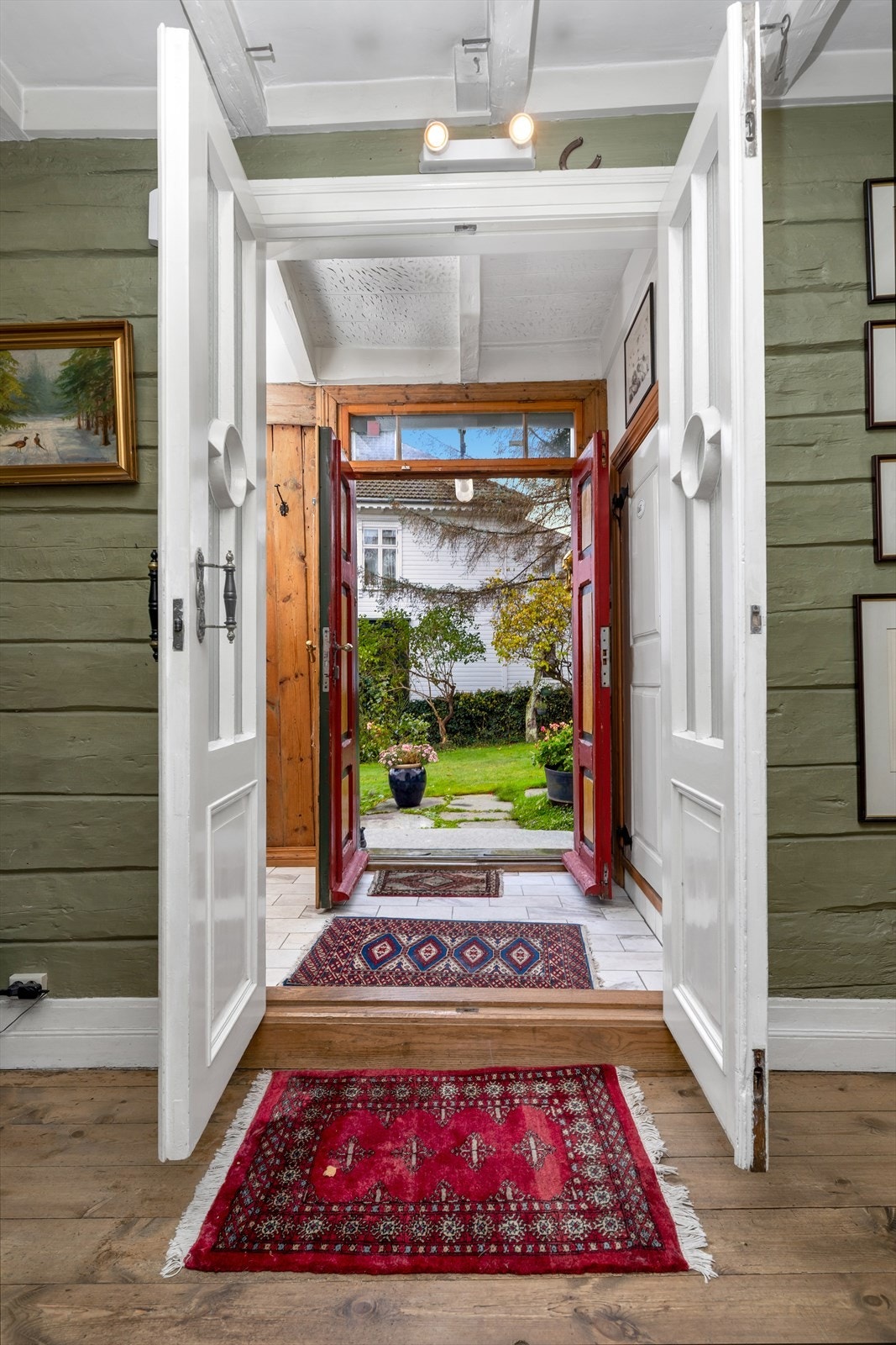 Dobbeltdører leder ut til en frodig hage, og gir enkel tilgang til uteområdet. Galleribilde