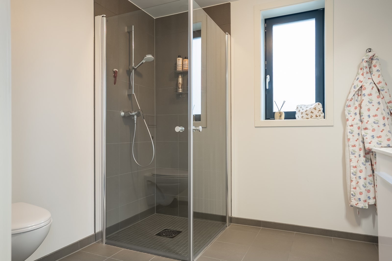 Pent, flislagt bad av god størrelse. Her får du fasiliteter som vegghengt toalett, dusjhjørne, behagelig gulvvarme og en stilren innredning. Galleribilde