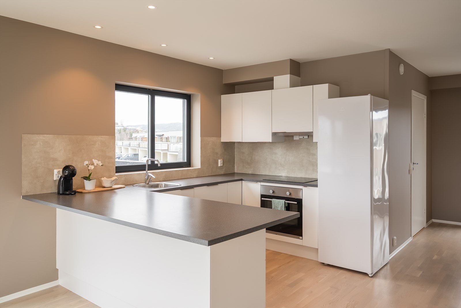 Stilrent og tidløst hjørnekjøkken med helintegrerte hvitevarer og frokostbar. Galleribilde