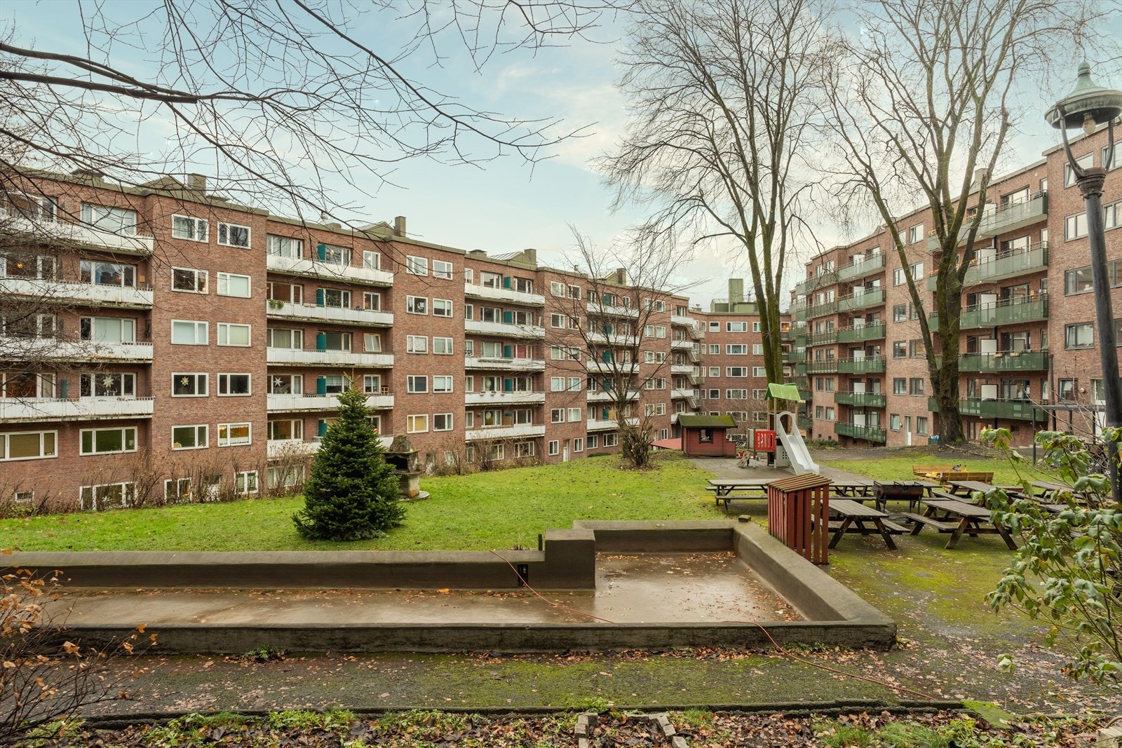 Frodig og pent opparbeidet gårdsrom med flere sittegrupper, sykkelparkering, lekeplass og grill. Galleribilde