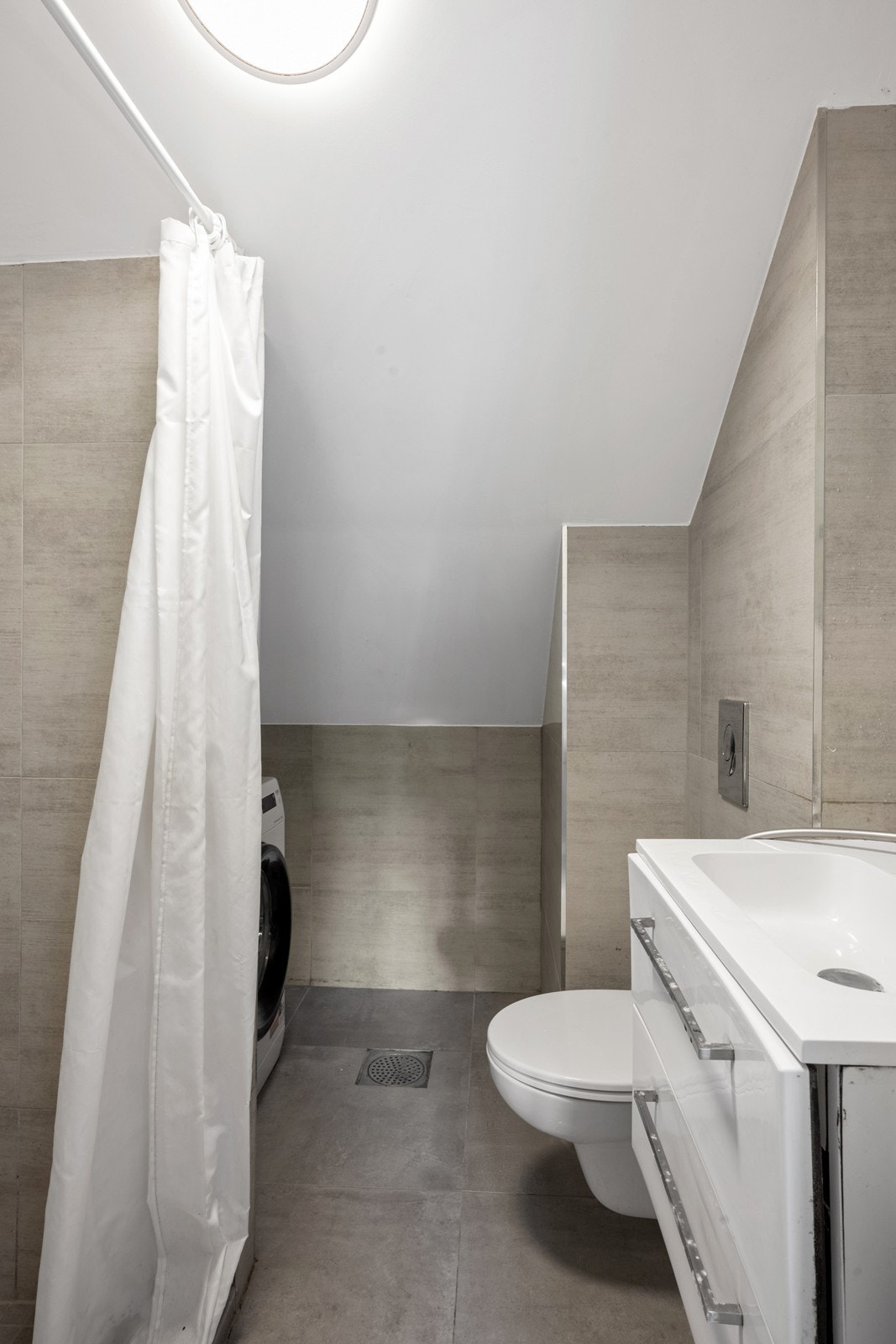 Flislagt bad i 2. etasje med varme i gulvet. Her er det dusjnisje, wc, servantinnredning og opplegg for vaskemaskin Galleribilde