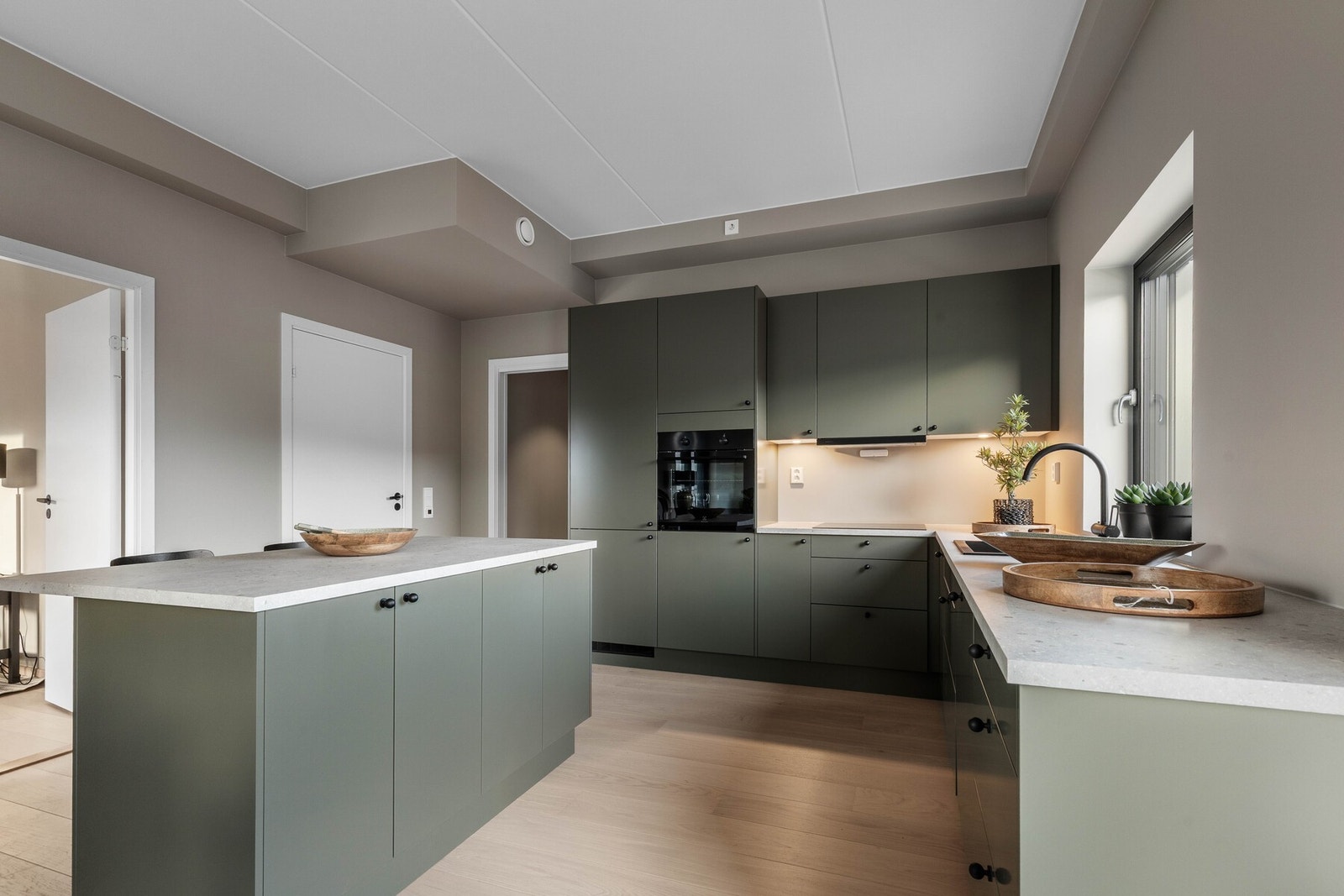 Kjøkkenet fra Sigdal har moderne, glatte fronter og sort benkeplate med nedfelt vask. Galleribilde