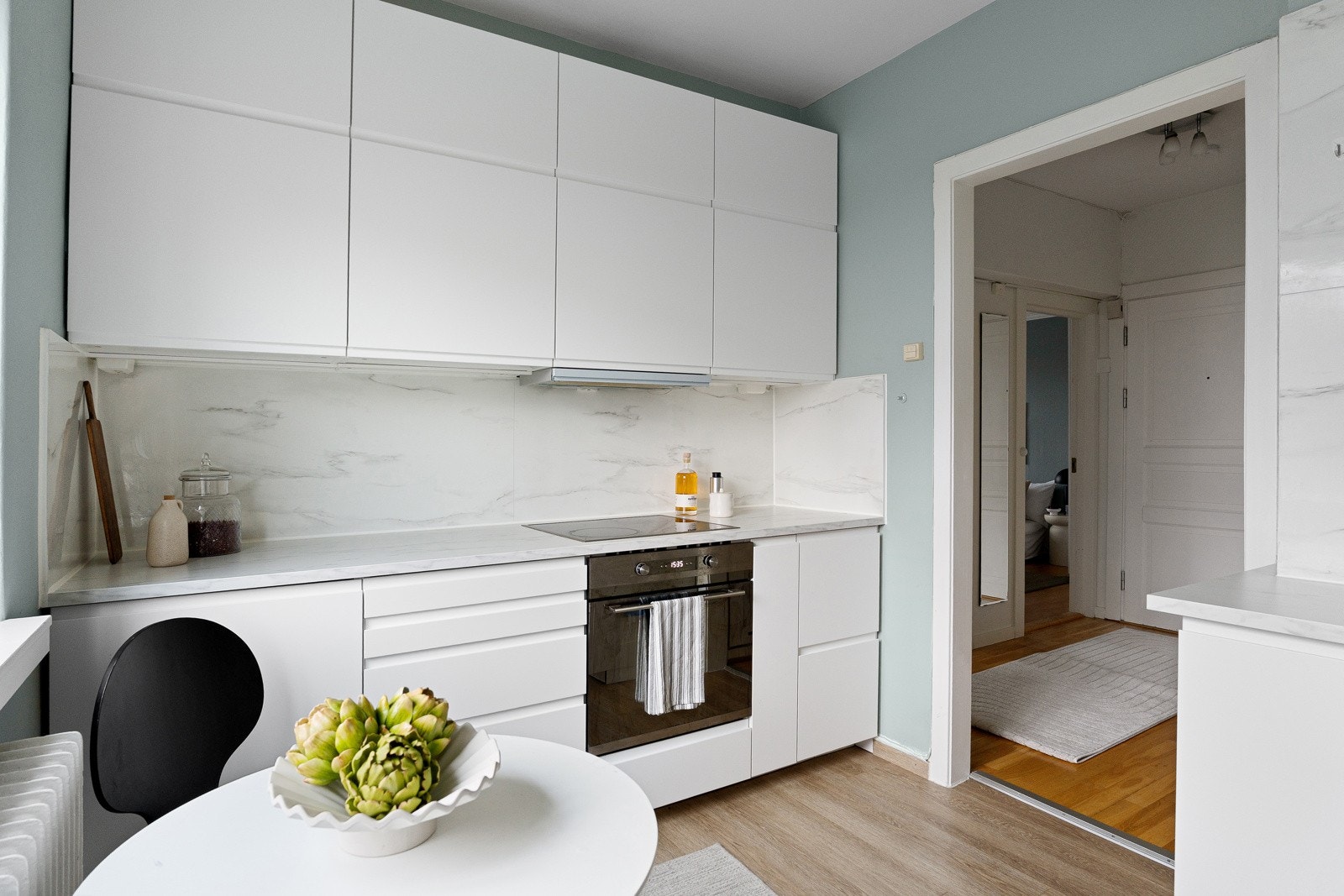 Stilren kjøkkeninnredning fra 2021 med hvite grepsfrie fronter, overskap og plater på vegger Galleribilde