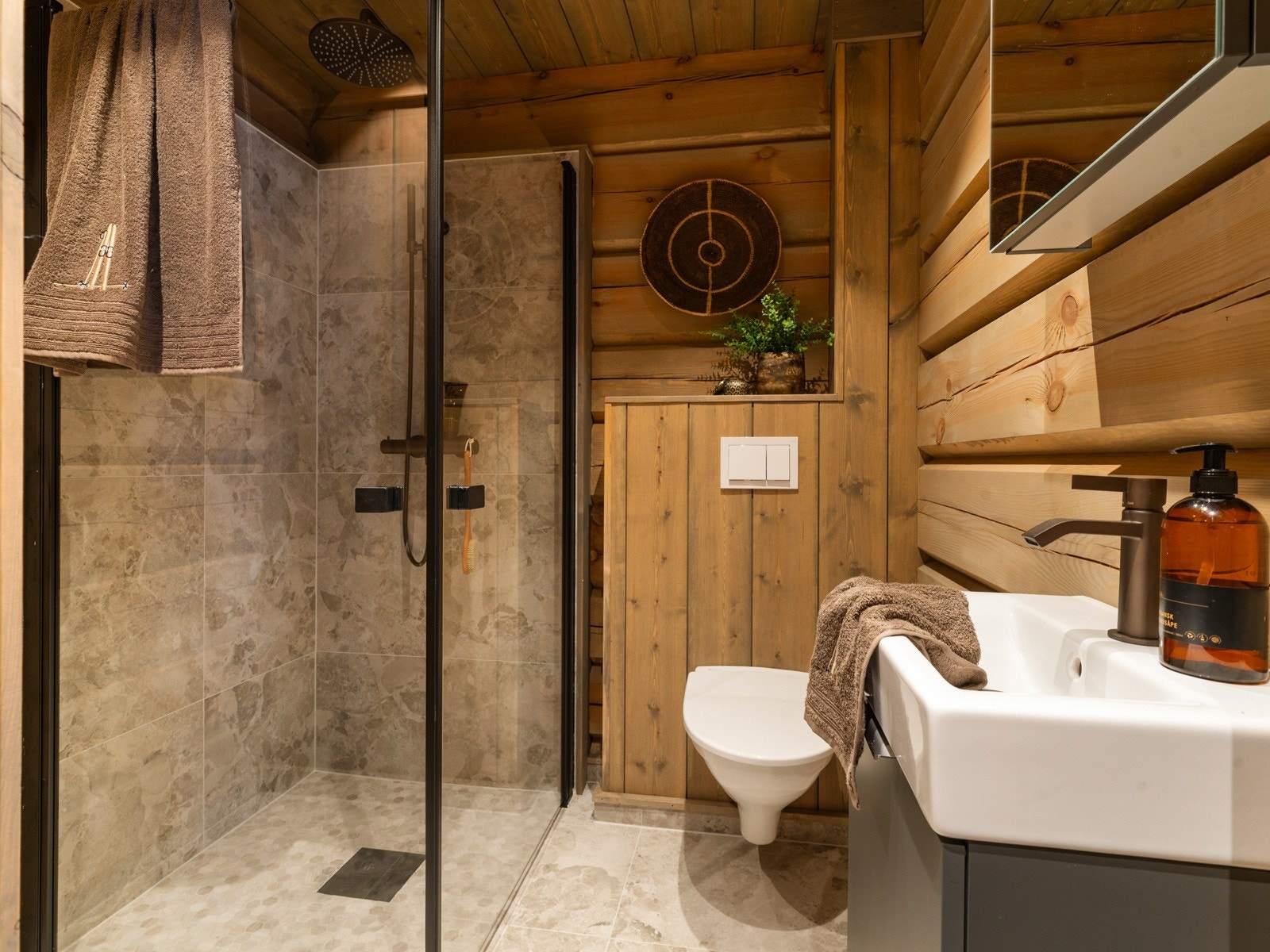 Badet er innredet med vegghengt klosett, servantinnredning med underskap, overskap med speil og romslig dusjhjørne. Galleribilde