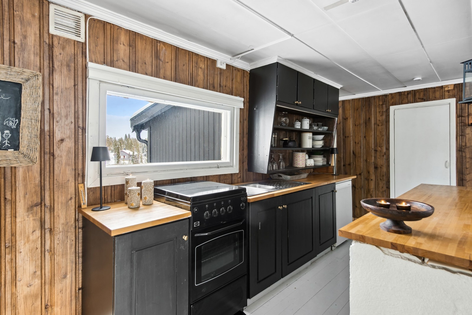 Kjøkkenet har innredning med malte profilerte fronter, plassbygget overskap med og uten dører. Galleribilde