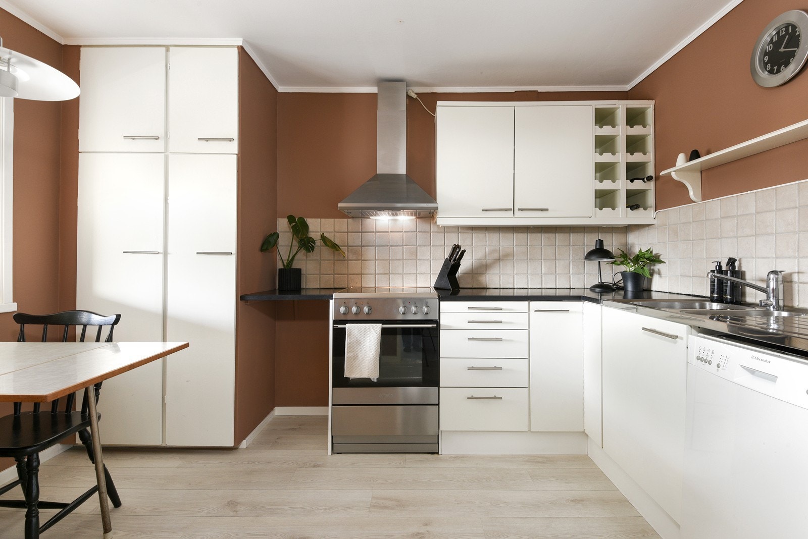 Kjøkkenet ligger adskilt fra stuen og har en L-formet utforming. Innredningen har hvite fronter, lys benkeplate og klassiske fliser over benk som gir et tidløst uttrykk. Galleribilde