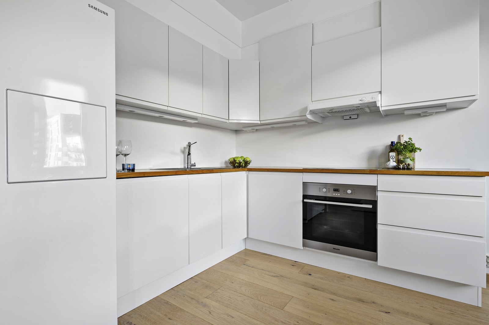 Pent kjøkkeninnredning med tilhørende hvitevarer. Det er satt inn et annet kjøleskap enn på bildet. Galleribilde