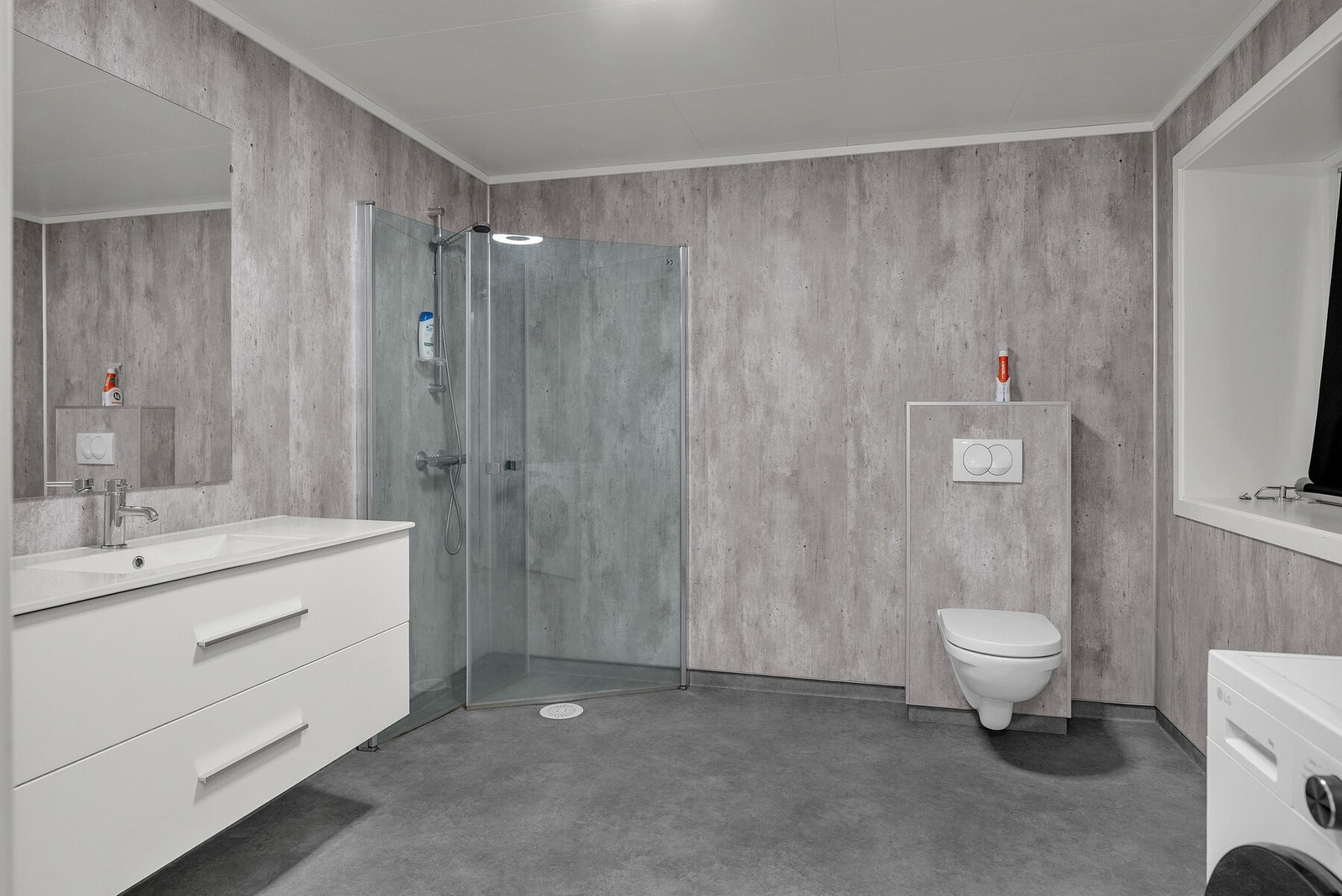 Bad/vaskerom er utstyrt med servant på skuffeseksjon, dusjhjørne og veggmontert wc. Galleribilde