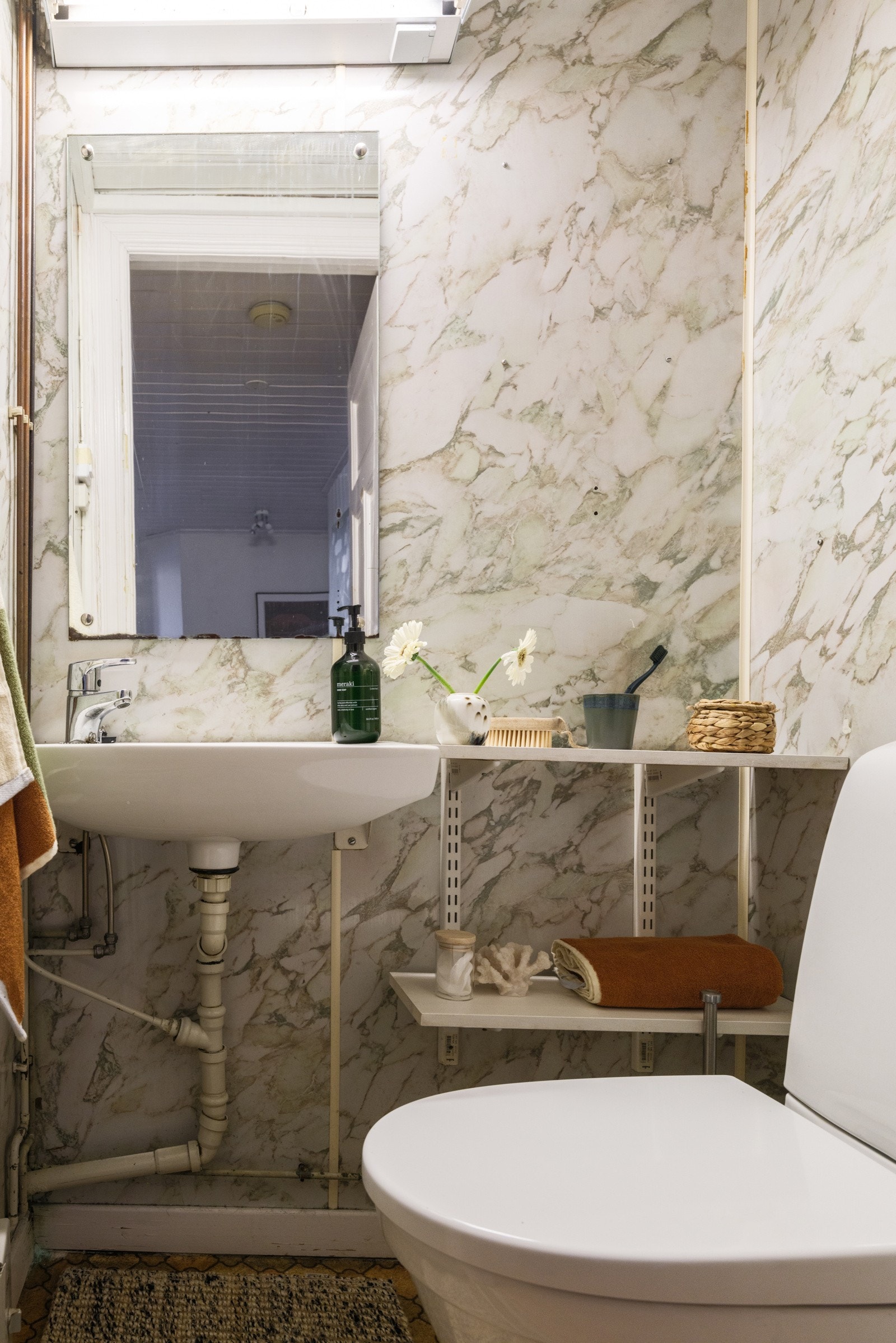 Separat toalettrom med vegghengt servant, speil med belysning over og gulvstående toalett.Innredning har passert mer enn 50% av levetid og fremstår utdatert. Galleribilde